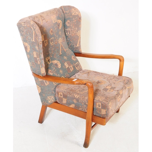 715 - A retro mid 20th century elm wood wingback armchair / lounge chair. The chair featuring bentwood arm... 