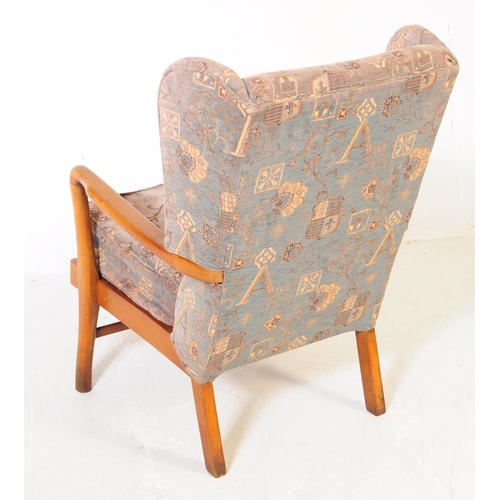 715 - A retro mid 20th century elm wood wingback armchair / lounge chair. The chair featuring bentwood arm... 