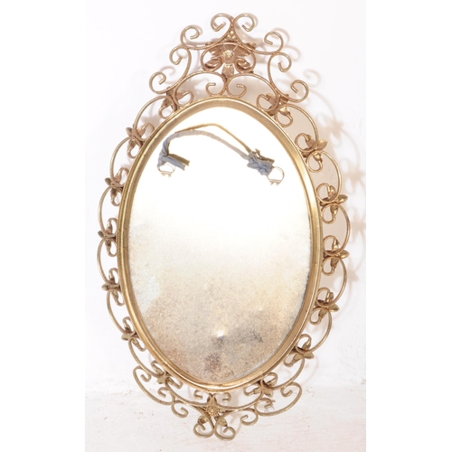 809 - A mid 20th century brass framed wall mirror. The mirror having scrolled metal work frame, with flora... 