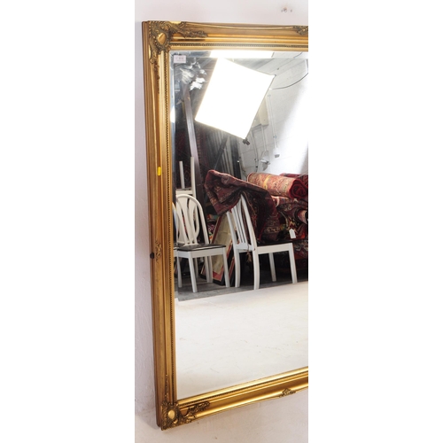 818 - A contemporary overmantle gilt mirror. Rectangular form with spandrel cartouche to corners with furt... 