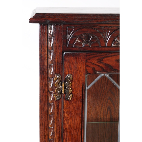 906 - A Jacobean revival oak wood glazed bookcase / display cabinet. The cabinet featuring two doors to fr... 