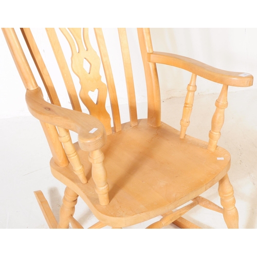 934 - A 20th century pine wood windsor style rocking armchair. The chair having shaped arm rests, raised o... 