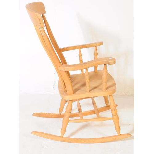 934 - A 20th century pine wood windsor style rocking armchair. The chair having shaped arm rests, raised o... 