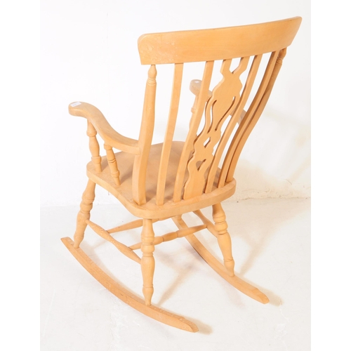 934 - A 20th century pine wood windsor style rocking armchair. The chair having shaped arm rests, raised o... 