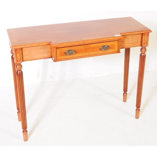 976 - A Sheraton revival mahogany breakfront writing table having reeded legs and cross banded top with bo... 