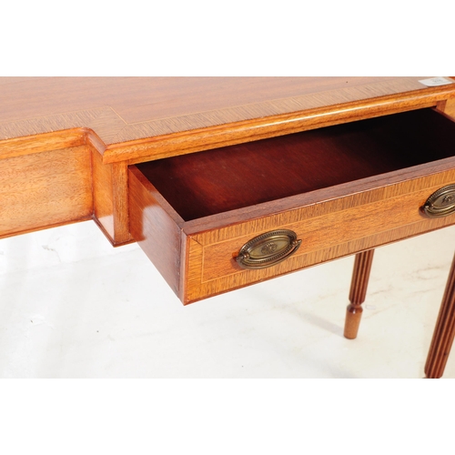 976 - A Sheraton revival mahogany breakfront writing table having reeded legs and cross banded top with bo... 