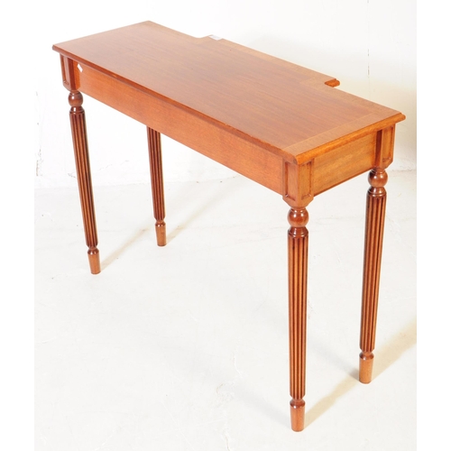 976 - A Sheraton revival mahogany breakfront writing table having reeded legs and cross banded top with bo... 