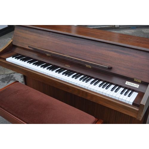 628 - Kimball - A mid 20th century Kimball piano in a walnut veneer case. The piano alongside long teak du... 