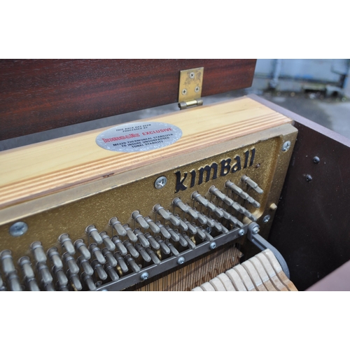 628 - Kimball - A mid 20th century Kimball piano in a walnut veneer case. The piano alongside long teak du... 