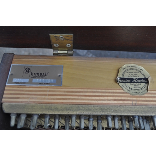 628 - Kimball - A mid 20th century Kimball piano in a walnut veneer case. The piano alongside long teak du... 