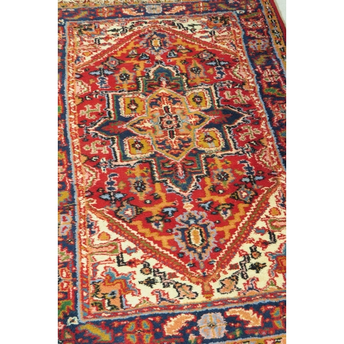 831 - Two late 20th century Persian manner wool rugs. The rugs both having red grounds, featuring large ce... 