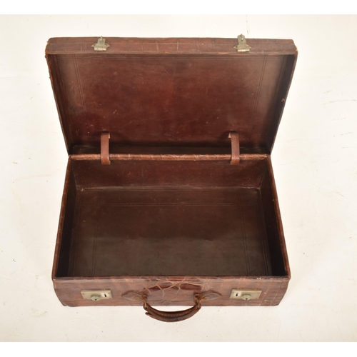 404 - An early 20th century crocodile skin leather suitcase / travel case. The case with metal locks & lea... 