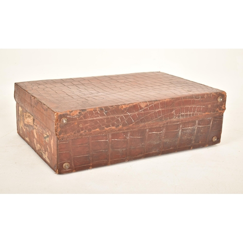 404 - An early 20th century crocodile skin leather suitcase / travel case. The case with metal locks & lea... 