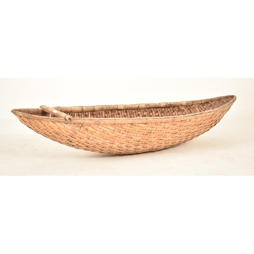 353 - A large African tribal hand woven wicker rattan canoe shaped cot / basket. The basket having a reinf... 