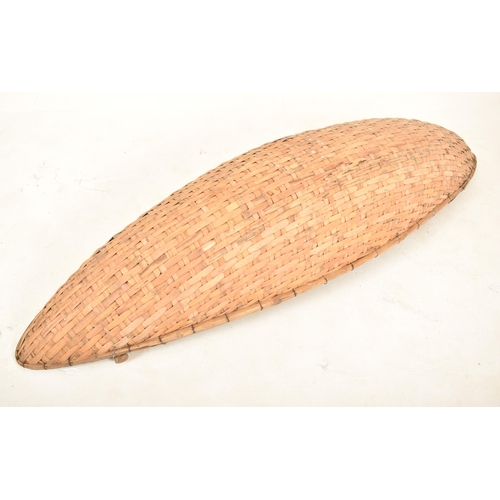 353 - A large African tribal hand woven wicker rattan canoe shaped cot / basket. The basket having a reinf... 