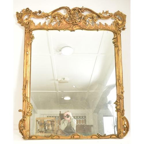 254 - A large Rococo inspired 19th century gilt wood & gesso overmantel mirror. The mirror having a intric... 