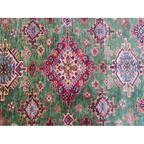 478 - A 20th century Kazak wool floor carpet rug from Kazakstan. Green and red ground with repeating patte... 