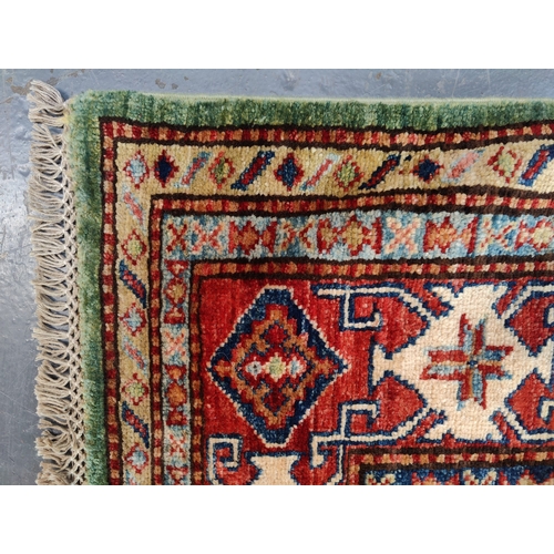 478 - A 20th century Kazak wool floor carpet rug from Kazakstan. Green and red ground with repeating patte... 