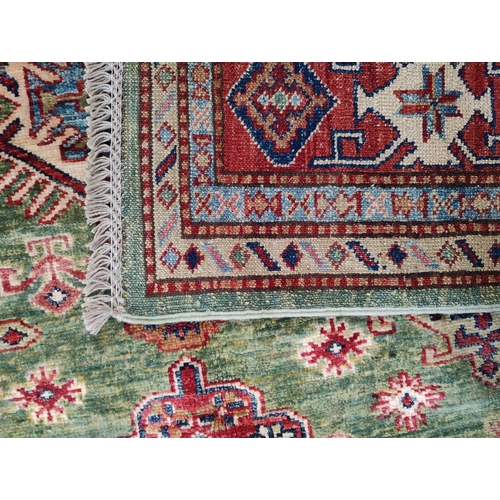 478 - A 20th century Kazak wool floor carpet rug from Kazakstan. Green and red ground with repeating patte... 