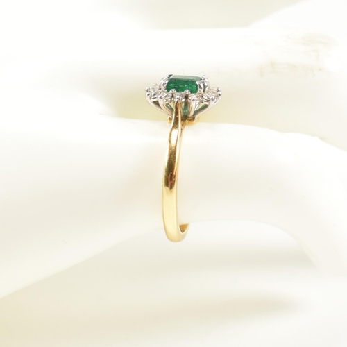 102 - A hallmarked 18ct gold, emerald and diamond cluster ring. The ring having a central emerald cut emer... 