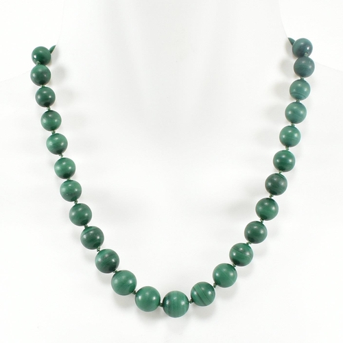 111 - A 14ct gold and malachite bead necklace. The necklace strung with knotted well carved malachite bead... 