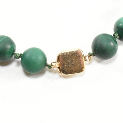 111 - A 14ct gold and malachite bead necklace. The necklace strung with knotted well carved malachite bead... 