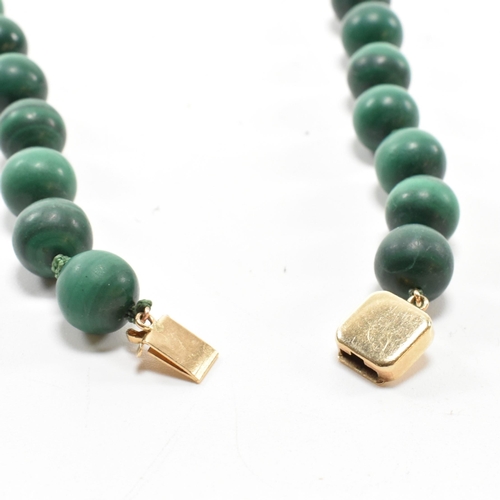 111 - A 14ct gold and malachite bead necklace. The necklace strung with knotted well carved malachite bead... 