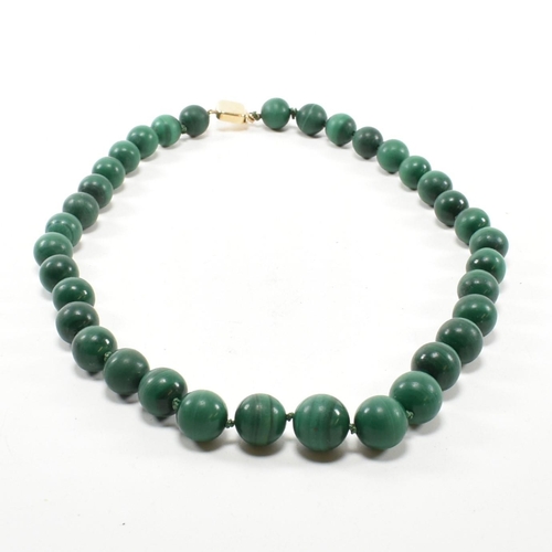 111 - A 14ct gold and malachite bead necklace. The necklace strung with knotted well carved malachite bead... 