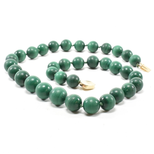 111 - A 14ct gold and malachite bead necklace. The necklace strung with knotted well carved malachite bead... 