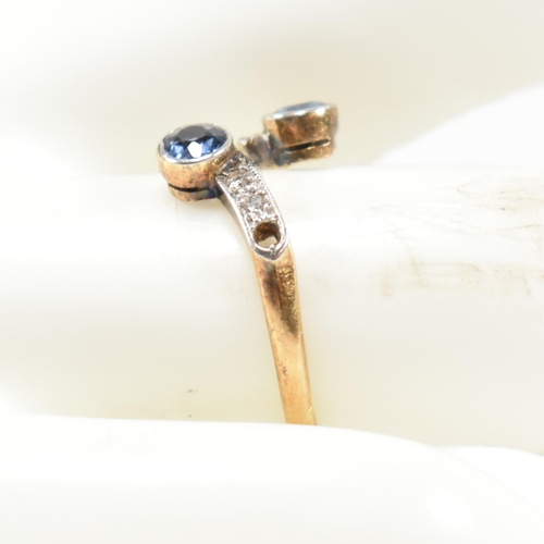 114 - An 18ct gold, sapphire and diamond cross over ring. The ring having two bezel set round cut sapphire... 