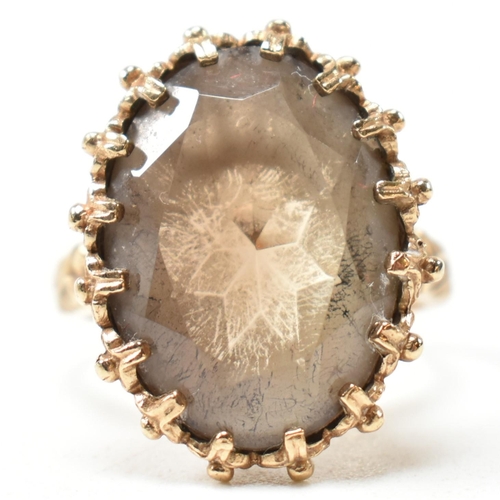 151 - A hallmarked 9ct gold and smoky quartz dress ring. The ring set with an oval mixed cut smoky quartz ... 