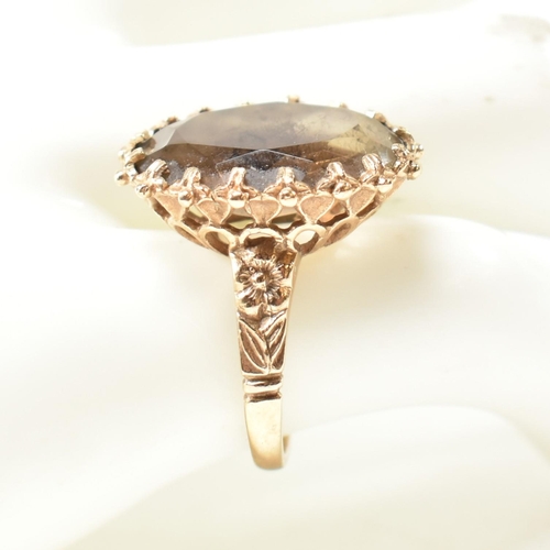 151 - A hallmarked 9ct gold and smoky quartz dress ring. The ring set with an oval mixed cut smoky quartz ... 