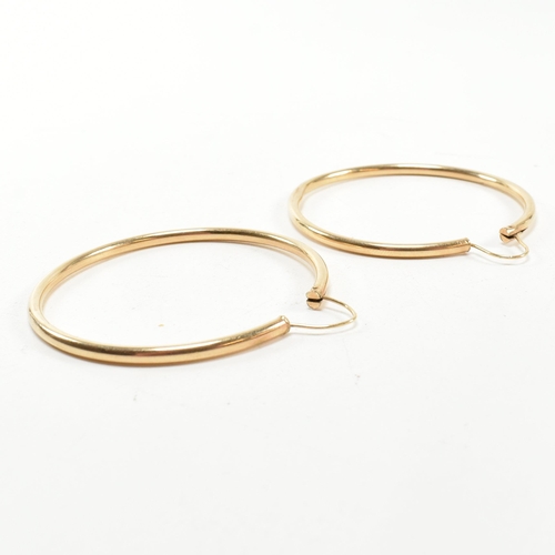 164 - A pair of gold hoop earrings. The gold hollow hoop earrings having endless fasteners. Unmarked, surf... 