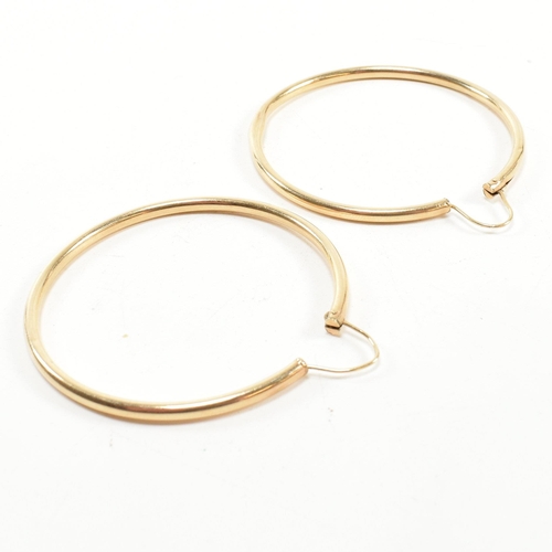 164 - A pair of gold hoop earrings. The gold hollow hoop earrings having endless fasteners. Unmarked, surf... 