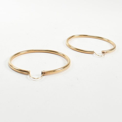 164 - A pair of gold hoop earrings. The gold hollow hoop earrings having endless fasteners. Unmarked, surf... 