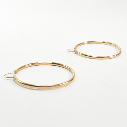 164 - A pair of gold hoop earrings. The gold hollow hoop earrings having endless fasteners. Unmarked, surf... 