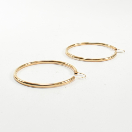 164 - A pair of gold hoop earrings. The gold hollow hoop earrings having endless fasteners. Unmarked, surf... 