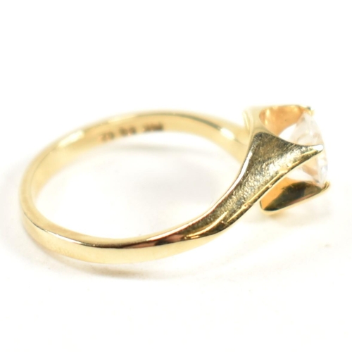 165 - A hallmarked 14ct gold and CZ crossover ring. The ring having a single round cut CZ set in a 14ct go... 