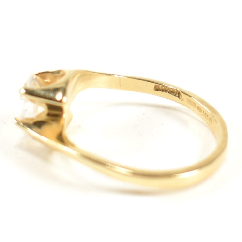 165 - A hallmarked 14ct gold and CZ crossover ring. The ring having a single round cut CZ set in a 14ct go... 