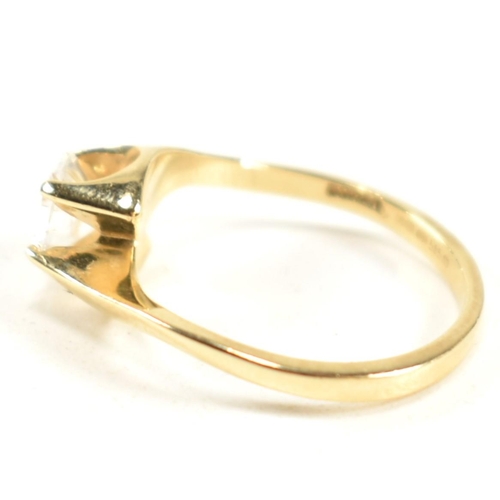 165 - A hallmarked 14ct gold and CZ crossover ring. The ring having a single round cut CZ set in a 14ct go... 