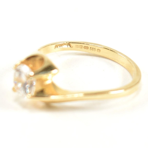 165 - A hallmarked 14ct gold and CZ crossover ring. The ring having a single round cut CZ set in a 14ct go... 