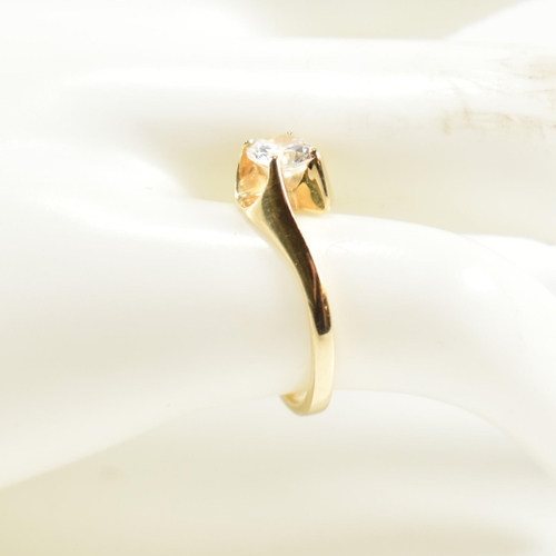 165 - A hallmarked 14ct gold and CZ crossover ring. The ring having a single round cut CZ set in a 14ct go... 