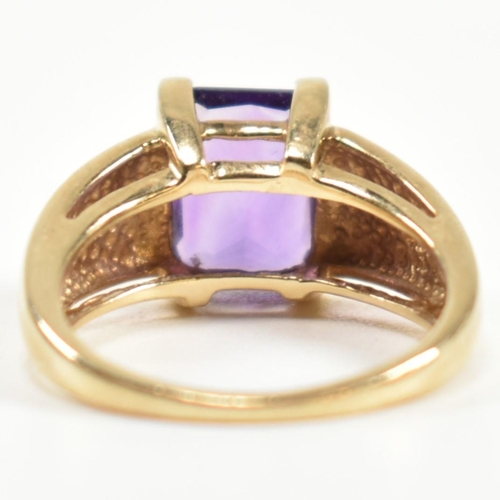 168 - A hallmarked 9ct gold and amethyst ring. The ring set with a central emerald cut amethyst in a domed... 