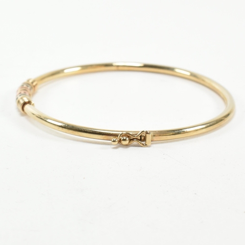 182 - A hallmarked 9ct gold hinged bangle. The gold hinged bangle having a tri-colour ring design to box c... 