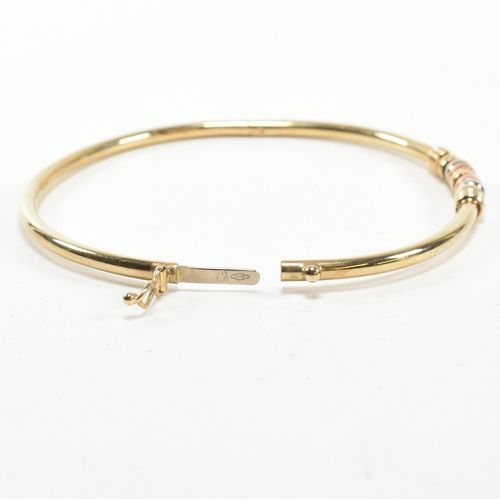 182 - A hallmarked 9ct gold hinged bangle. The gold hinged bangle having a tri-colour ring design to box c... 