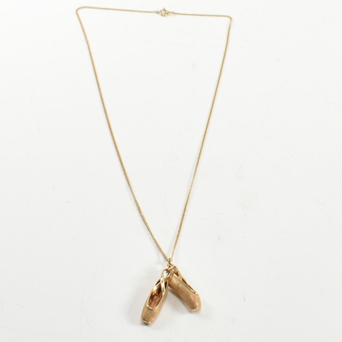 187 - A 14ct gold ballet shoes pendant necklace. The 14ct gold curb link chain necklace strung with a pend... 