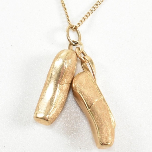 187 - A 14ct gold ballet shoes pendant necklace. The 14ct gold curb link chain necklace strung with a pend... 