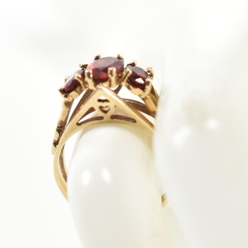 191 - A hallmarked 9ct gold and garnet trilogy ring. The ring set with three graduating four claw set oval... 