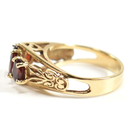 191 - A hallmarked 9ct gold and garnet trilogy ring. The ring set with three graduating four claw set oval... 