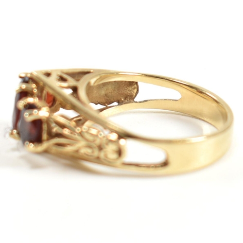 191 - A hallmarked 9ct gold and garnet trilogy ring. The ring set with three graduating four claw set oval... 